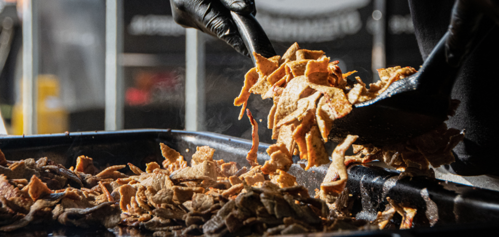 Een medewerker van Kebab Masters serveert verse kebab op een bakplaat in een foodtruck, klaar om te worden geserveerd op een evenement of catering.